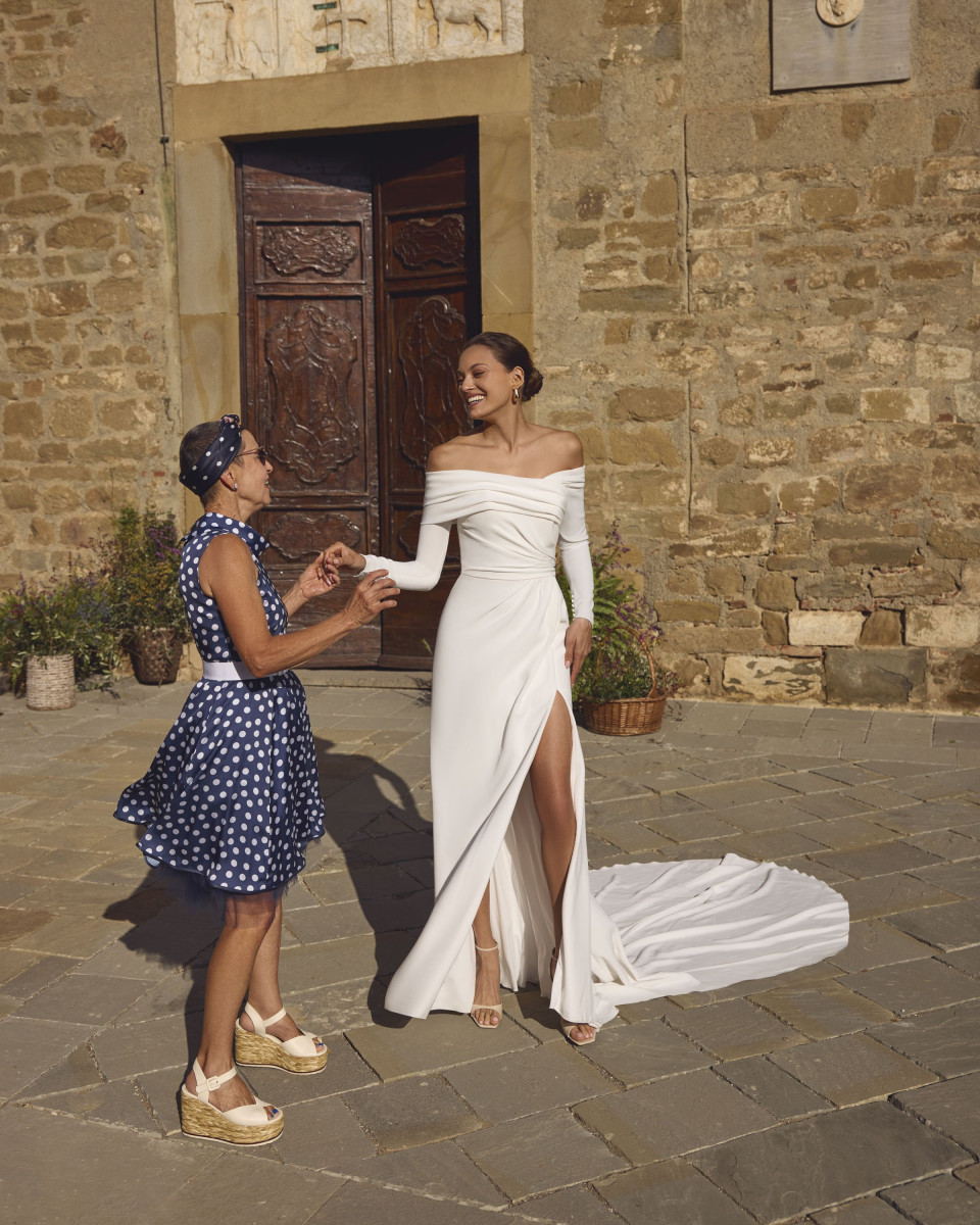 een vrouw in een witte jurk staat naast een vrouw in een blauw-wit gestipte jurk