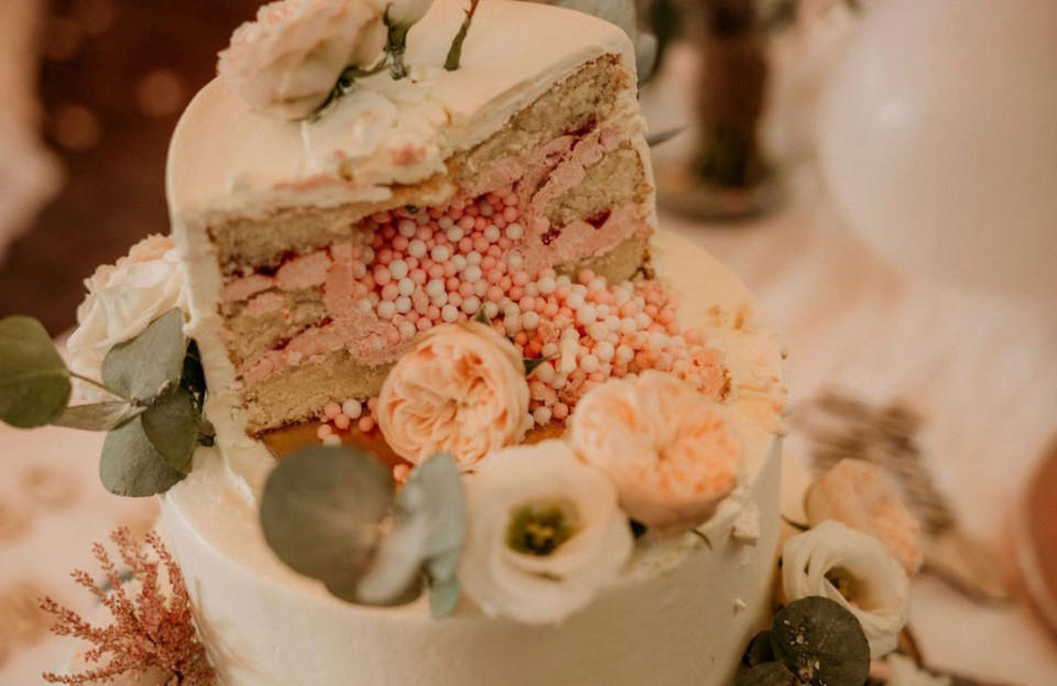 de binnenkant van een bruidstaart met witte glazuur en roze en witte bloemen aan de zijkant van de taart
