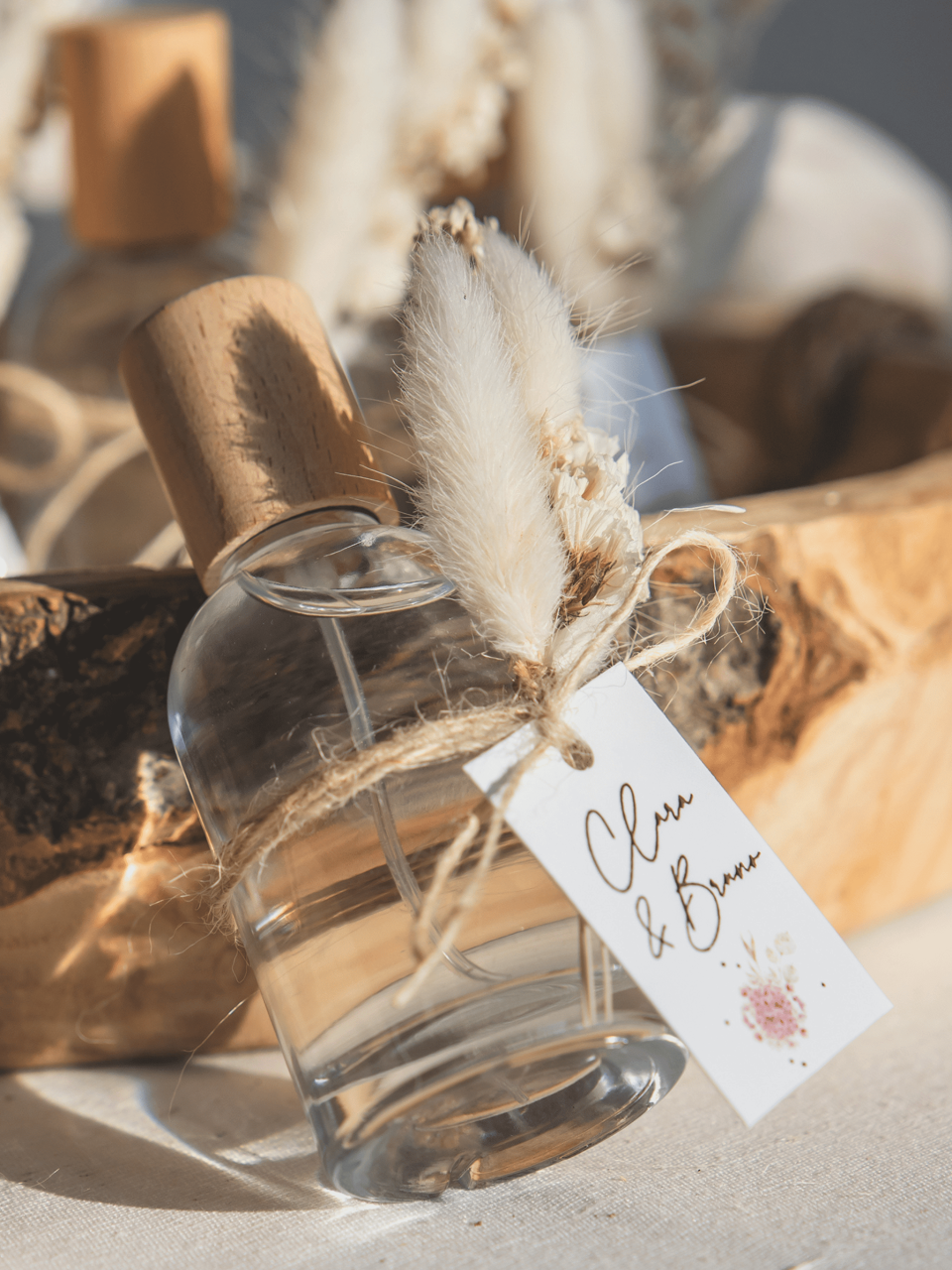 een close-up van een fles parfum met een label erop en een bos gedroogde bloemen op de achtergrond