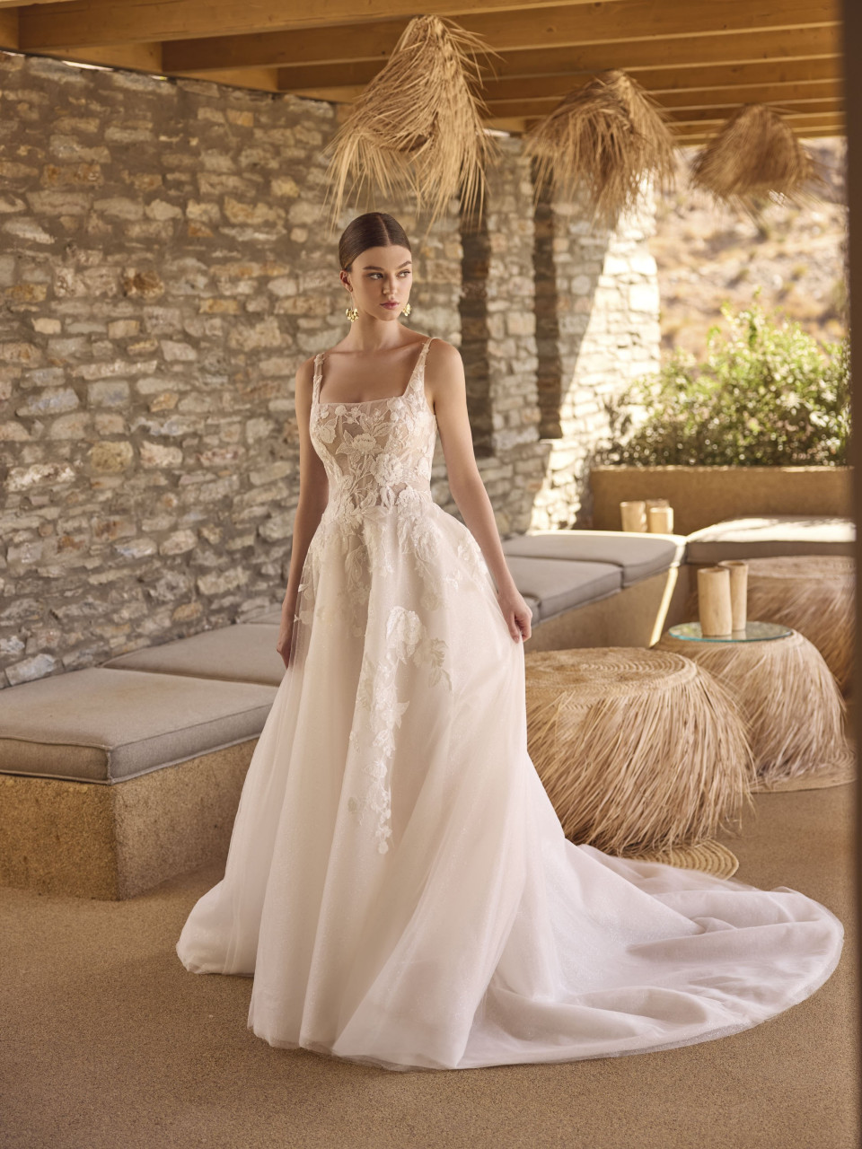 een vrouw in een trouwjurk die voor een stenen muur staat