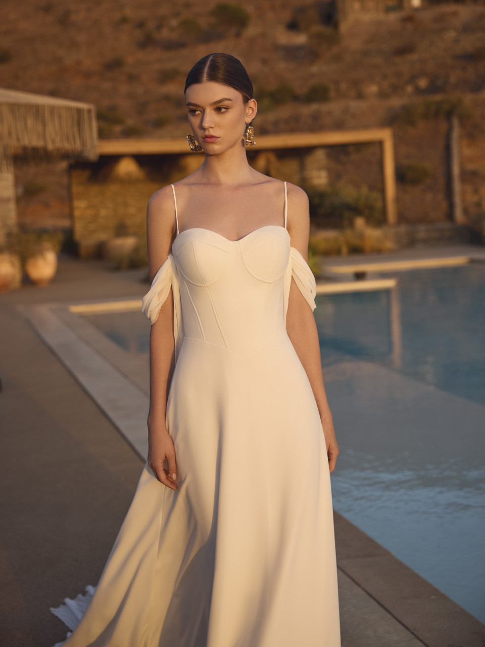 een vrouw in een witte jurk bij een zwembad