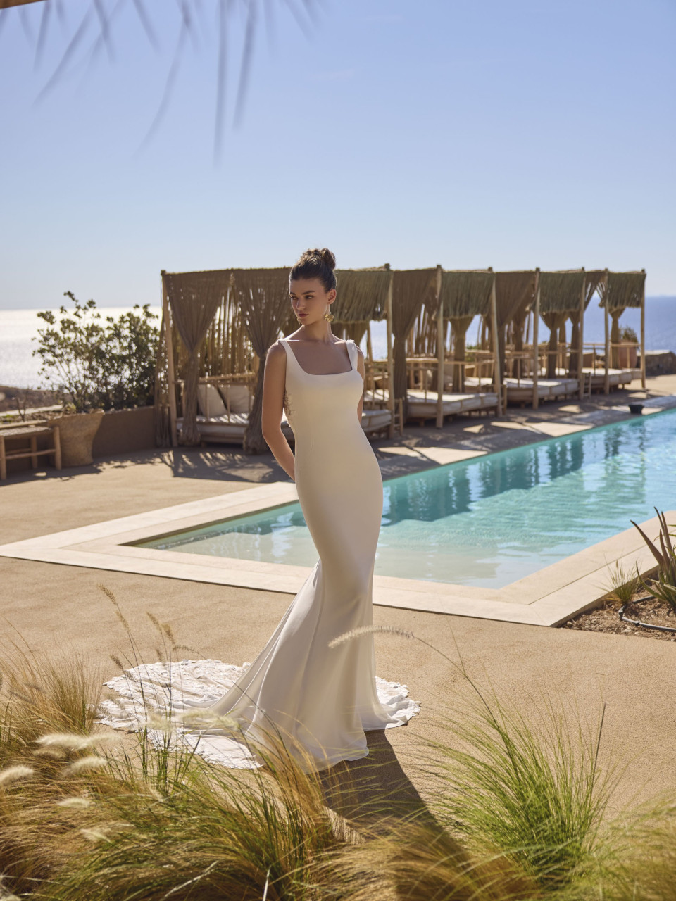 een vrouw in een trouwjurk die bij een zwembad staat