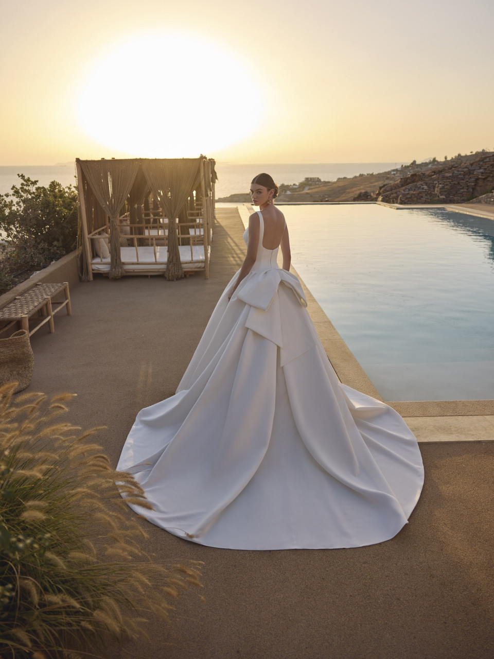 de achterkant van een vrouw in een trouwjurk die voor een zwembad staat