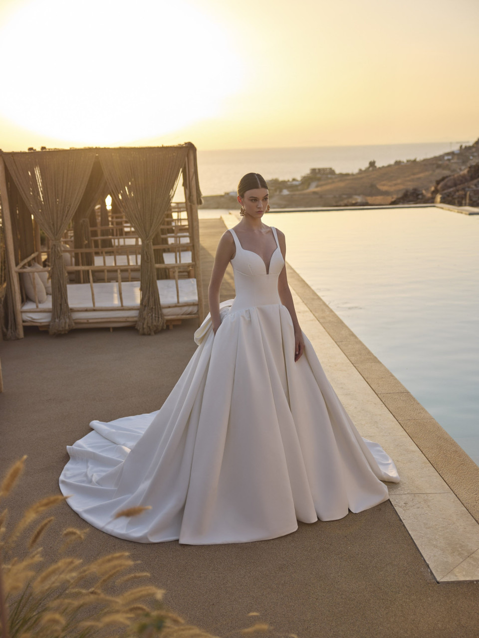 een vrouw in een trouwjurk die bij een zwembad staat