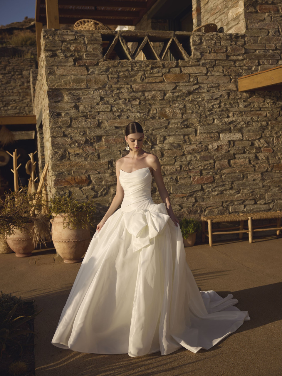 een vrouw in een trouwjurk die voor een stenen gebouw staat