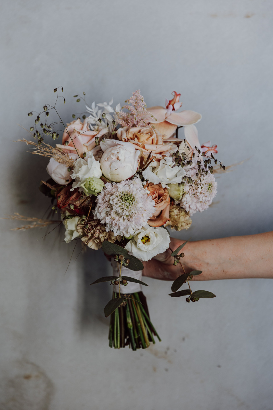 een persoon met een boeket bloemen tegen een muur