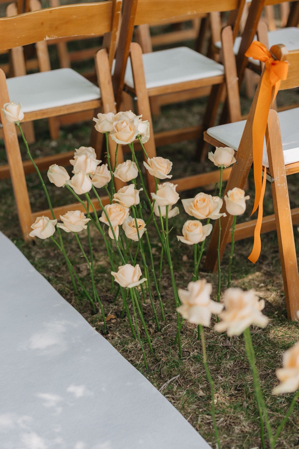 een rij houten stoelen met witte bloemen op de voorgrond