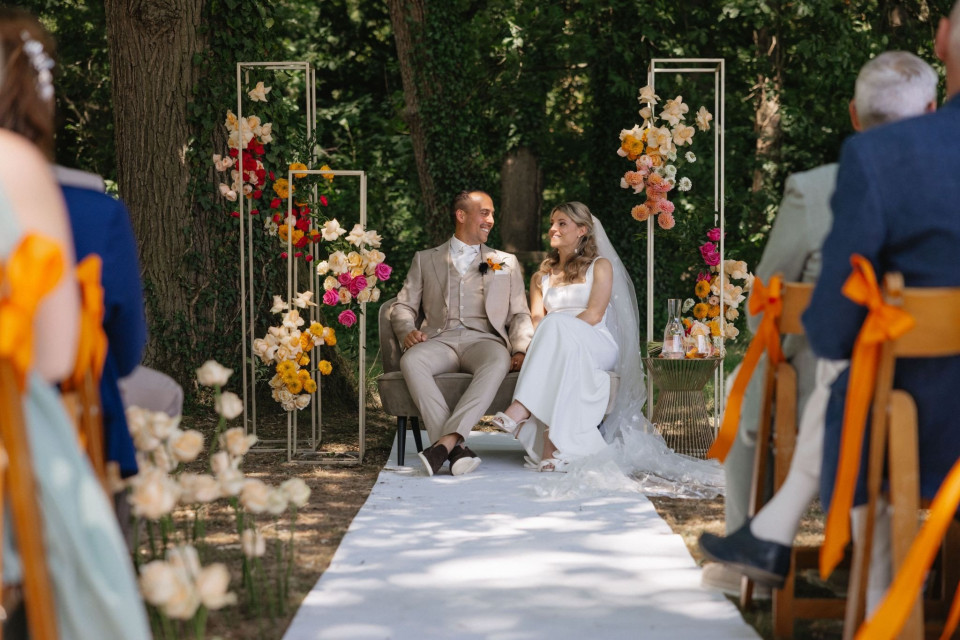 een bruid en bruidegom zittend op de gang van een huwelijksceremonie