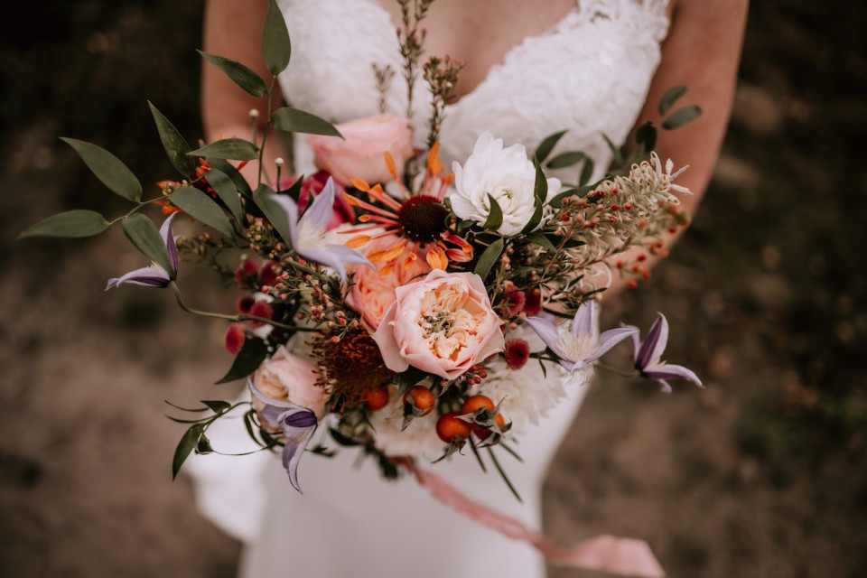 een vrouw in een trouwjurk met een boeket bloemen