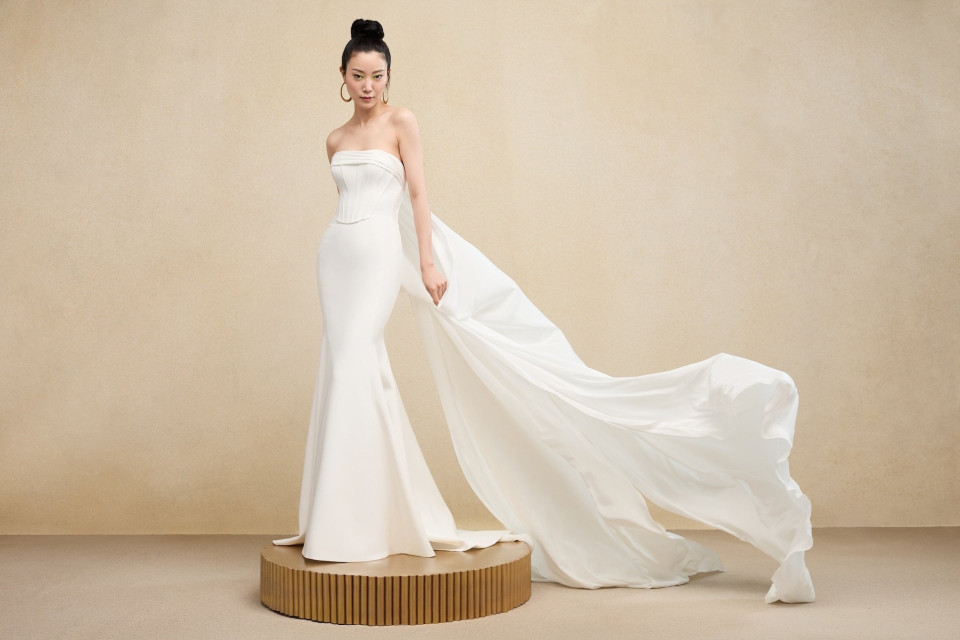 een model in een strapless witte trouwjurk poseert op een standaard