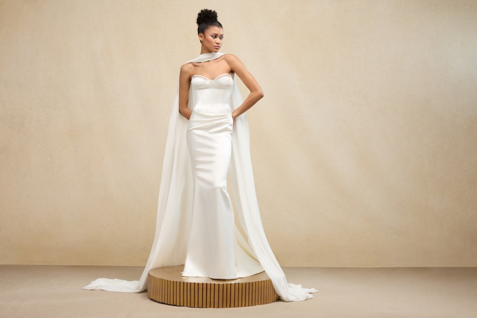 een model in een witte trouwjurk poseert op een voetstuk