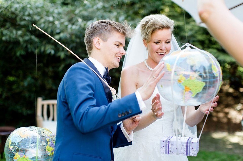 een bruid en bruidegom die een globe in hun handen vasthouden