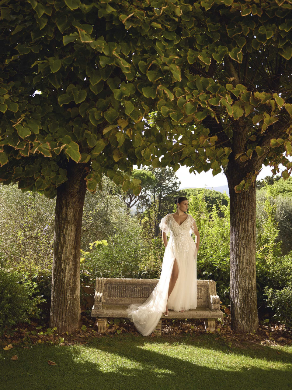een vrouw in een trouwjurk die op een bankje zit