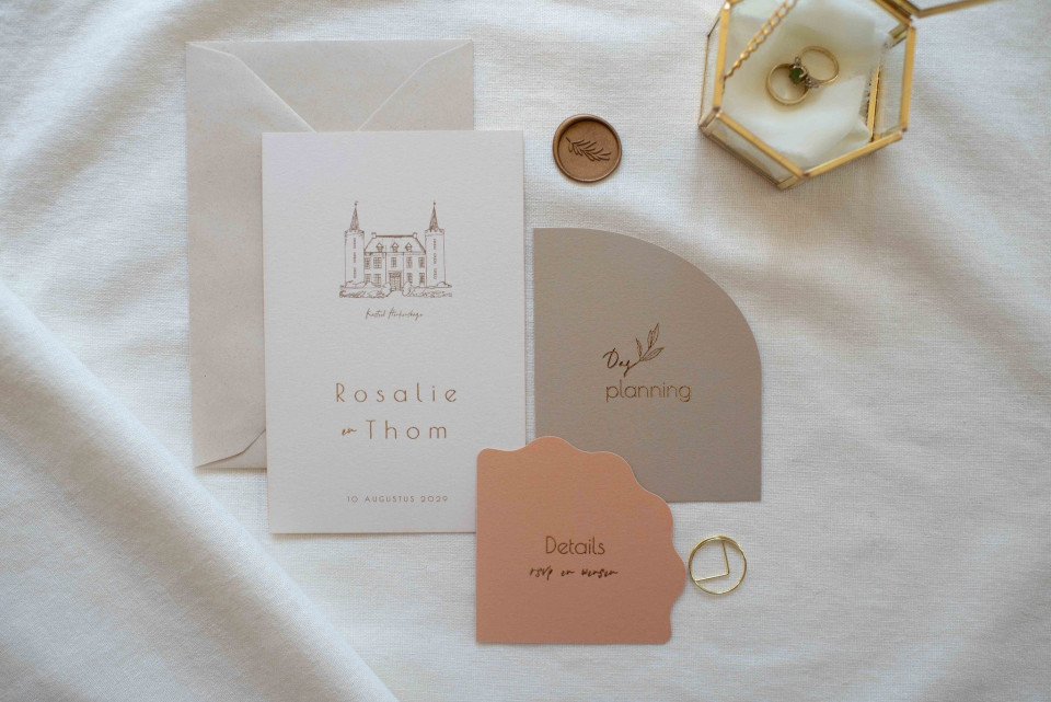 een close-up van de trouwstationery op het bed