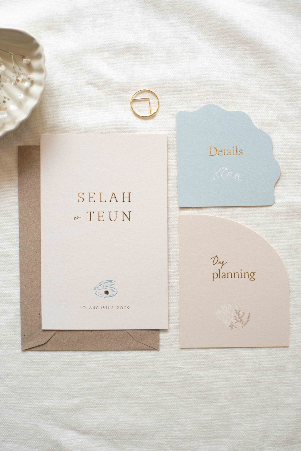 de inhoud van een trouwuitnodiging uitgespreid op een bed