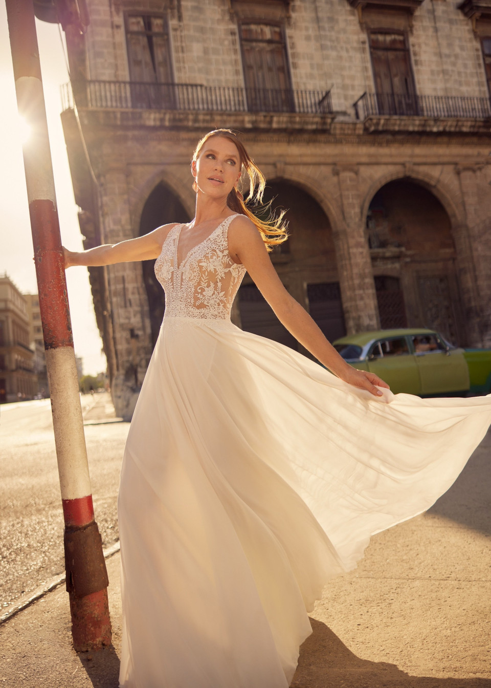 een vrouw in een trouwjurk poseert voor een foto op straat