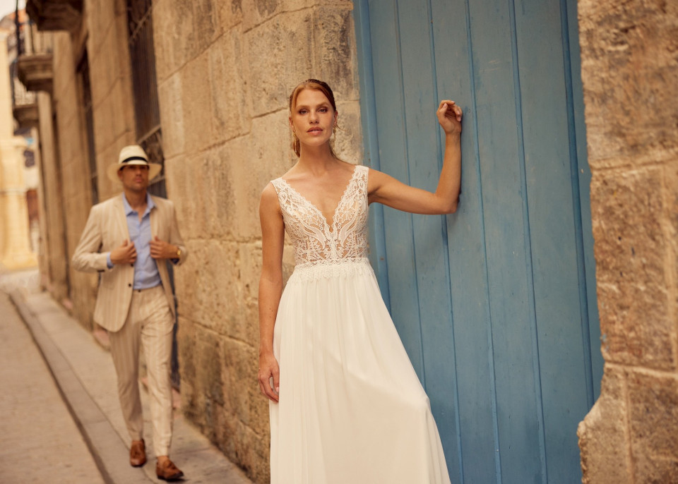 een man en vrouw in trouwkleding staan naast een blauwe deur