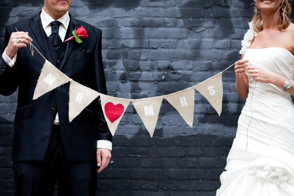 een bruid en bruidegom die een banner met harten vasthouden