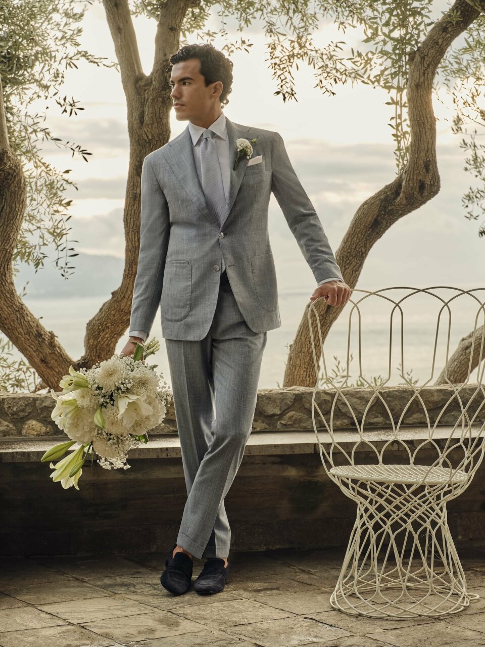 een man in een pak en stropdas die een boeket vasthoudt