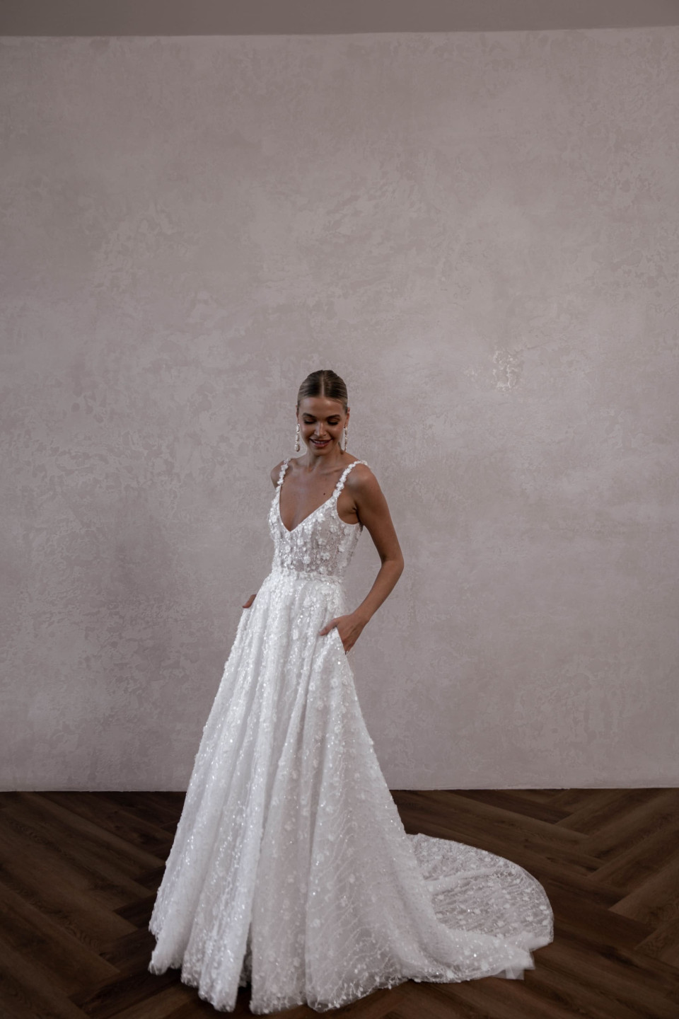 een bruid in een witte trouwjurk staat voor een muur