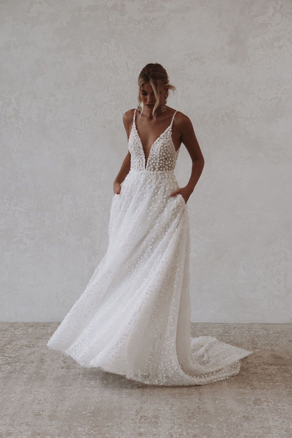 de bruid draagt een witte kanten trouwjurk met een diepe v-hals