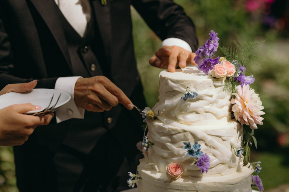 een man en een vrouw die een bruidstaart snijden met een mes en een mes slijper voor de taart