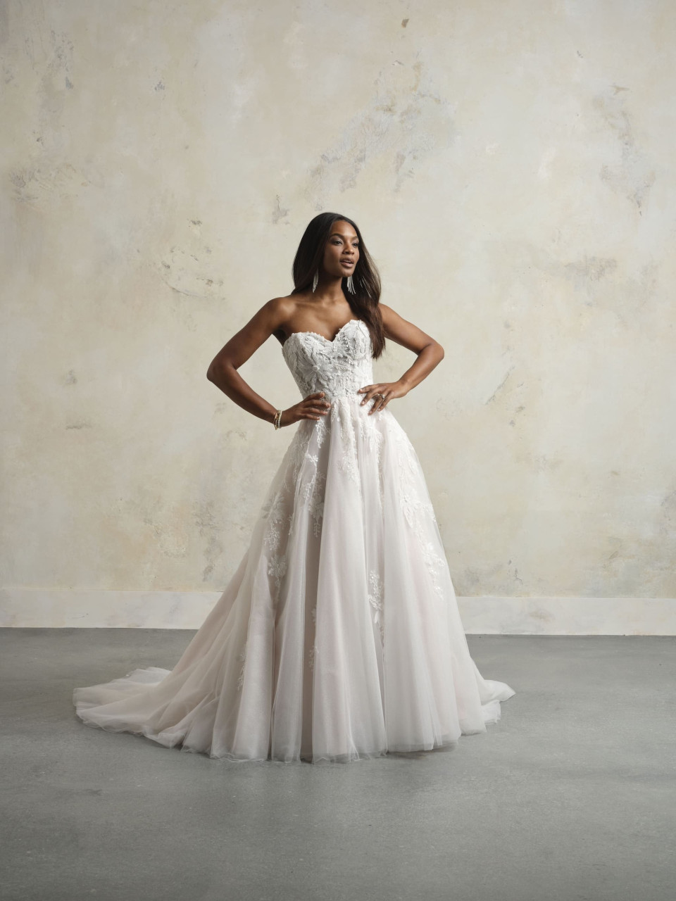 een vrouw in een strapless trouwjurk staat voor een muur