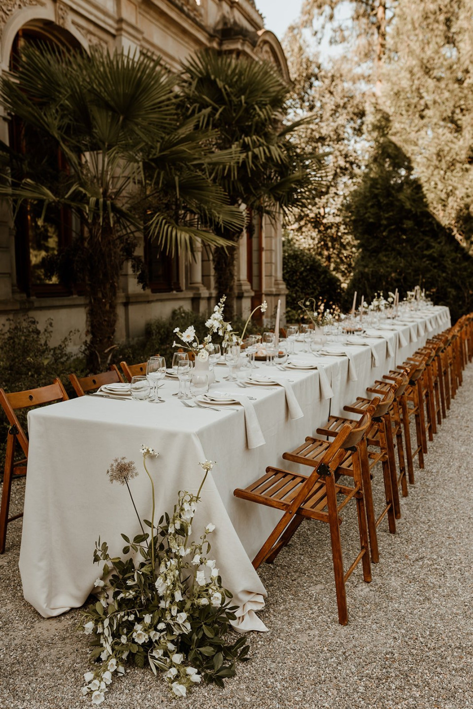 een lange tafel met witte tafelkleden en bloemen erop
