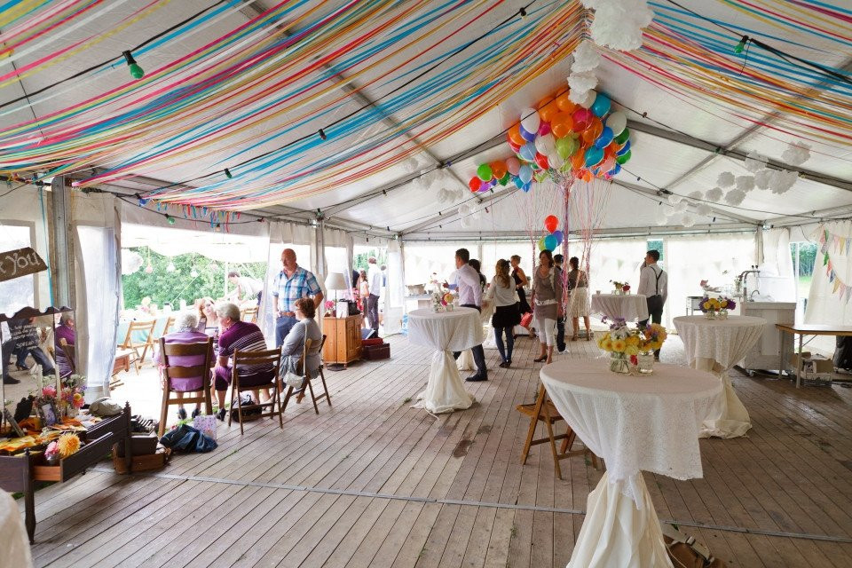 een tent met tafels en stoelen binnen met kleurrijke slingers