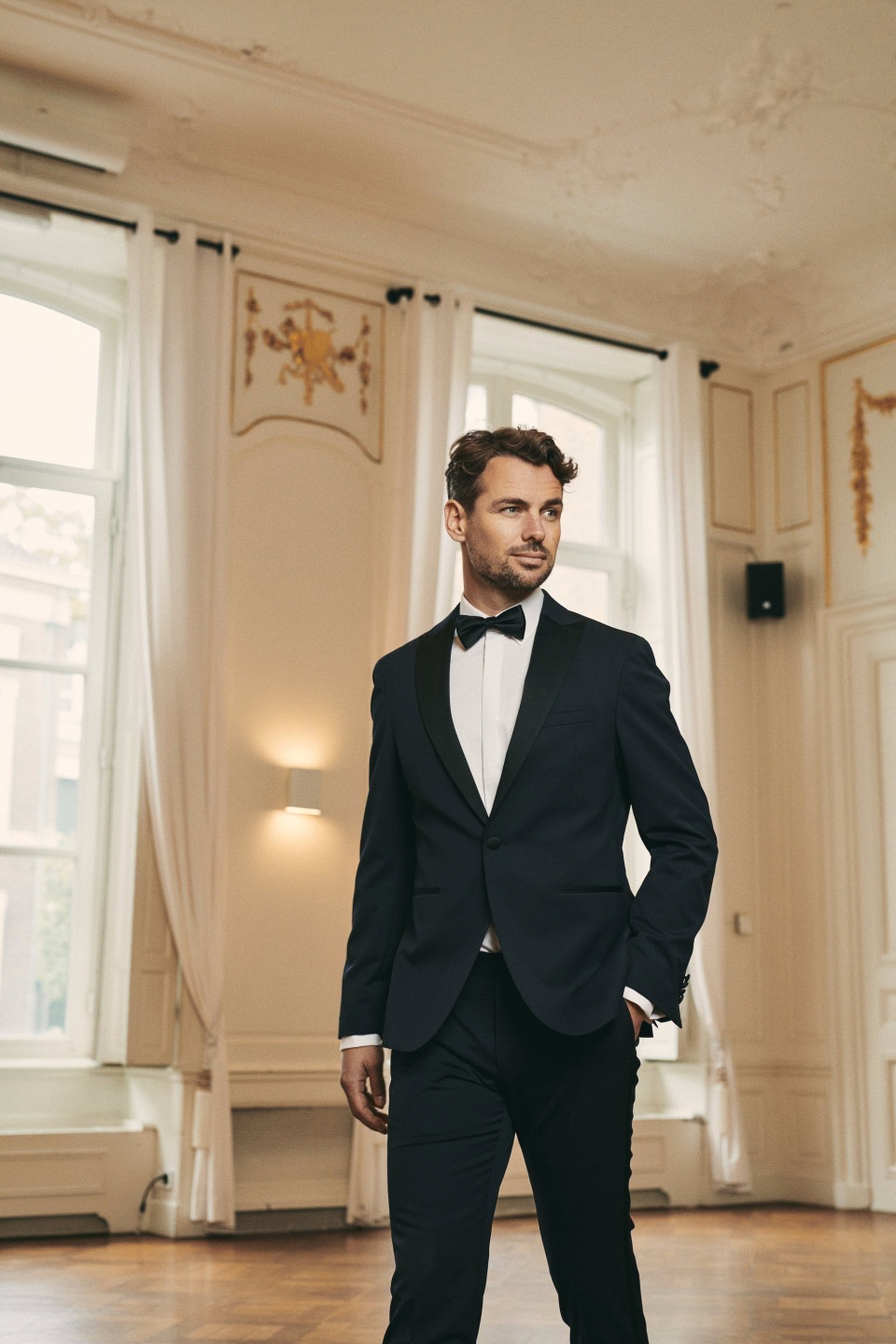 een man in een smoking staat in een kamer