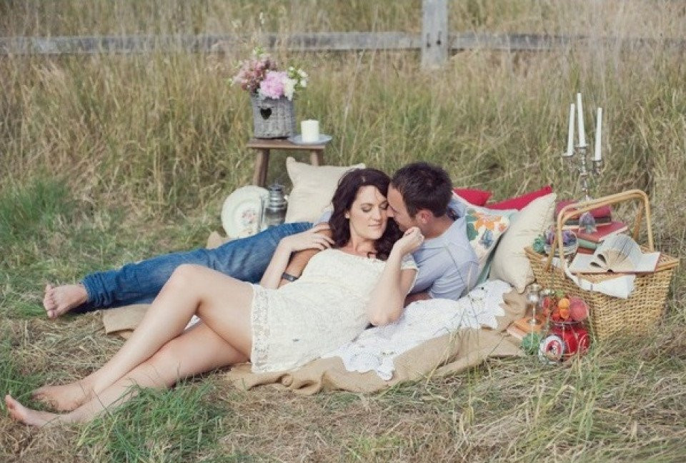 een stel ligt op een deken in een veld