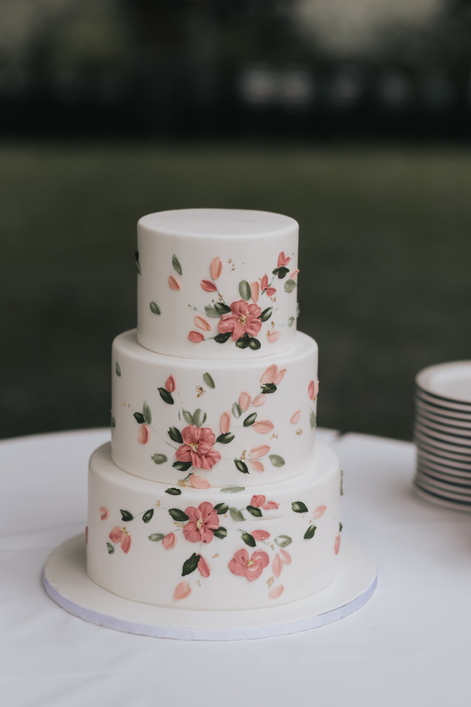 een drie-laags taart met roze bloemen erop
