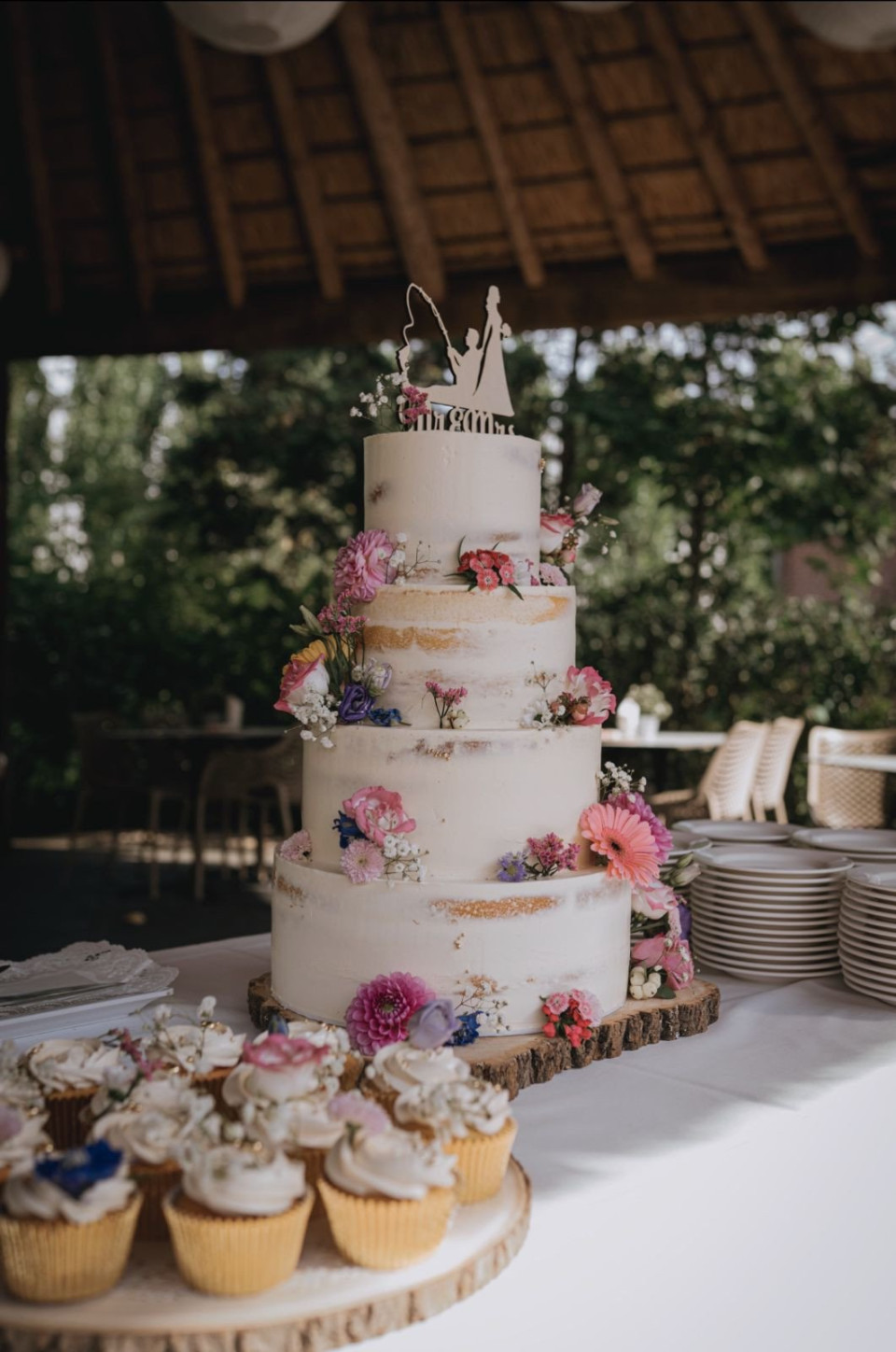 een bruidstaart en cupcakes op een tafel