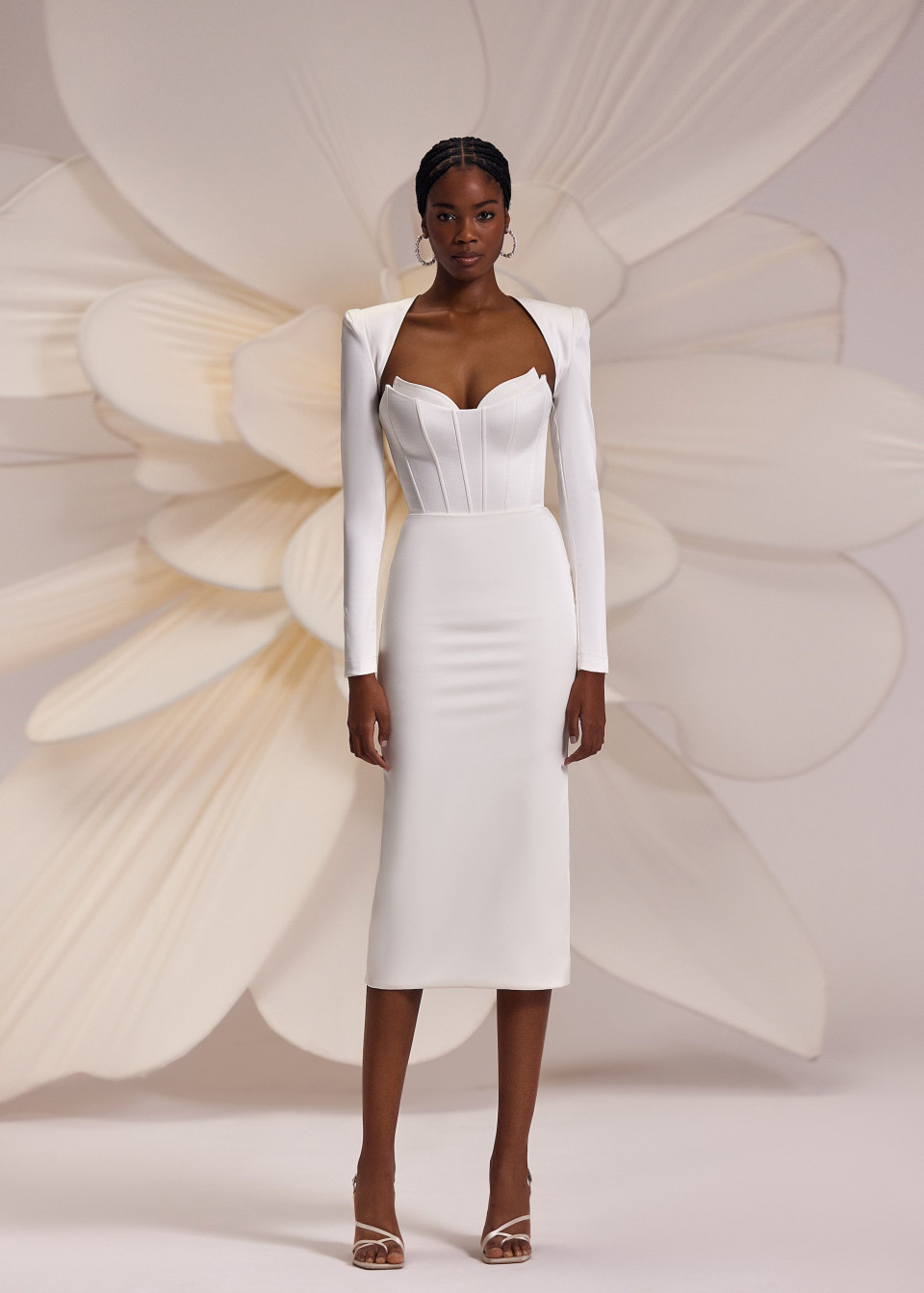 het model draagt een witte jurk met lange mouwen en een lange rok