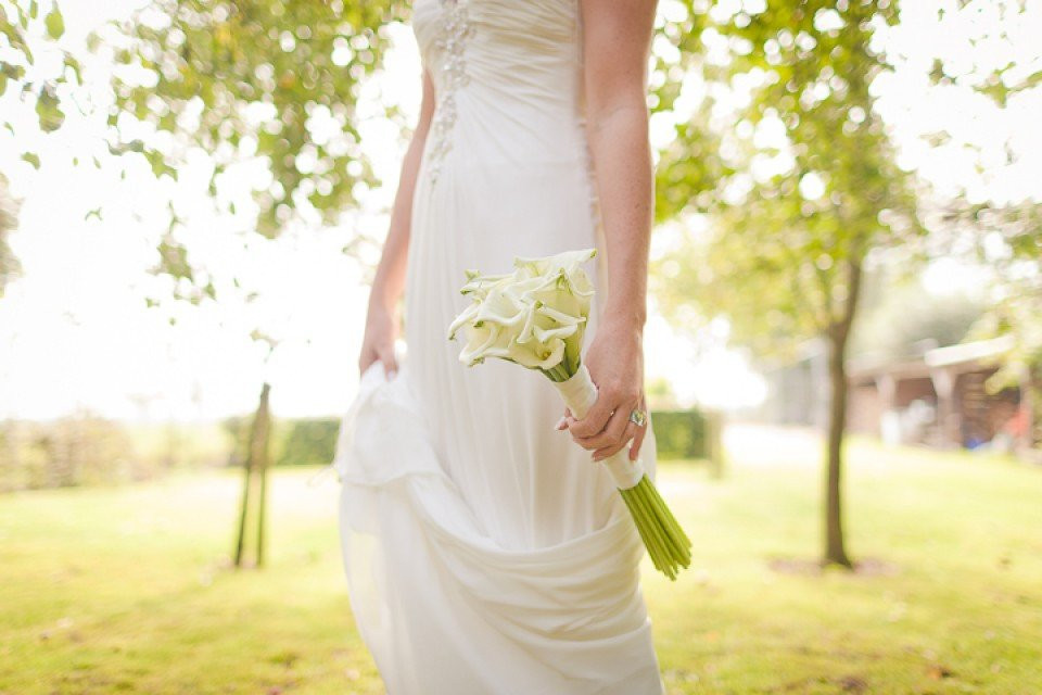 een bruid in een witte jurk die een boeket vasthoudt