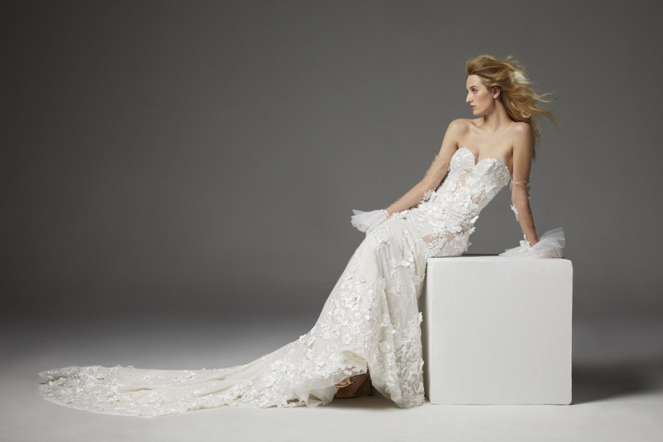 een vrouw in een trouwjurk zit op een witte doos