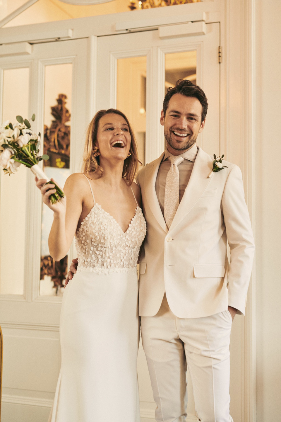 een bruid en bruidegom glimlachen voor de camera in hun trouwkleding