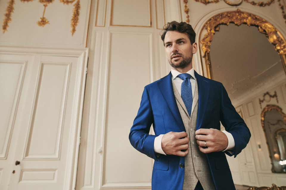 een man in een blauwe pak en stropdas staat in een kamer