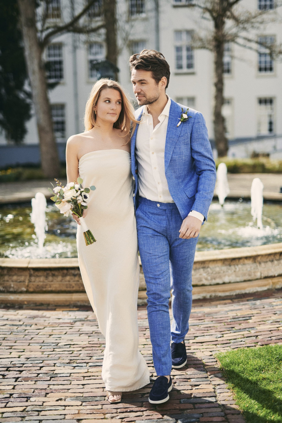 een bruid en bruidegom lopen voor een fontein