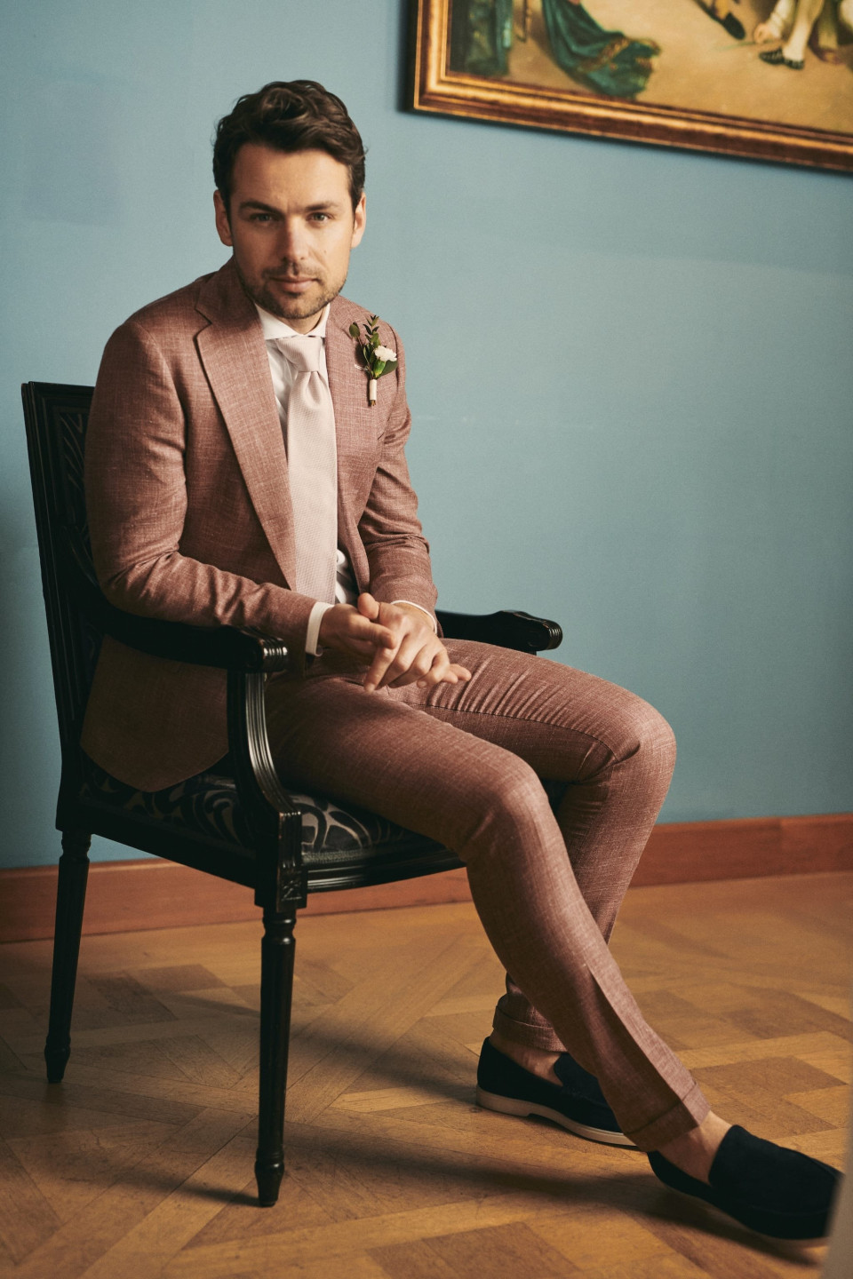 een man in een pak zit op een stoel