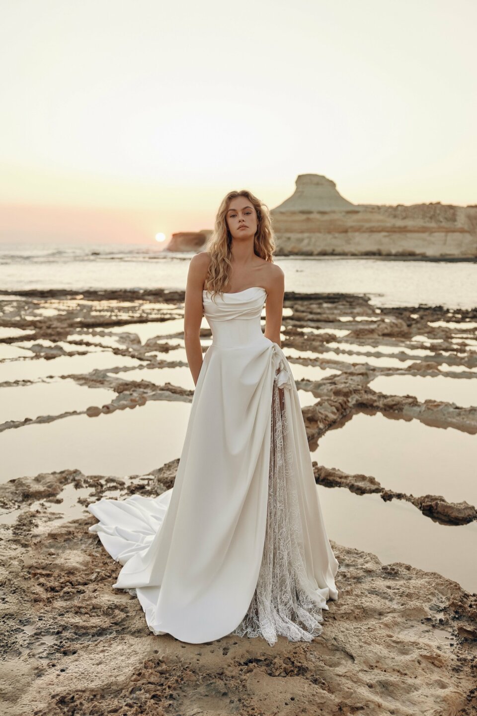 een vrouw in een trouwjurk die op het strand staat