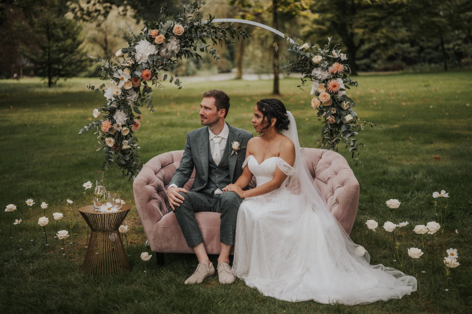 een bruid en bruidegom zittend op een roze bank