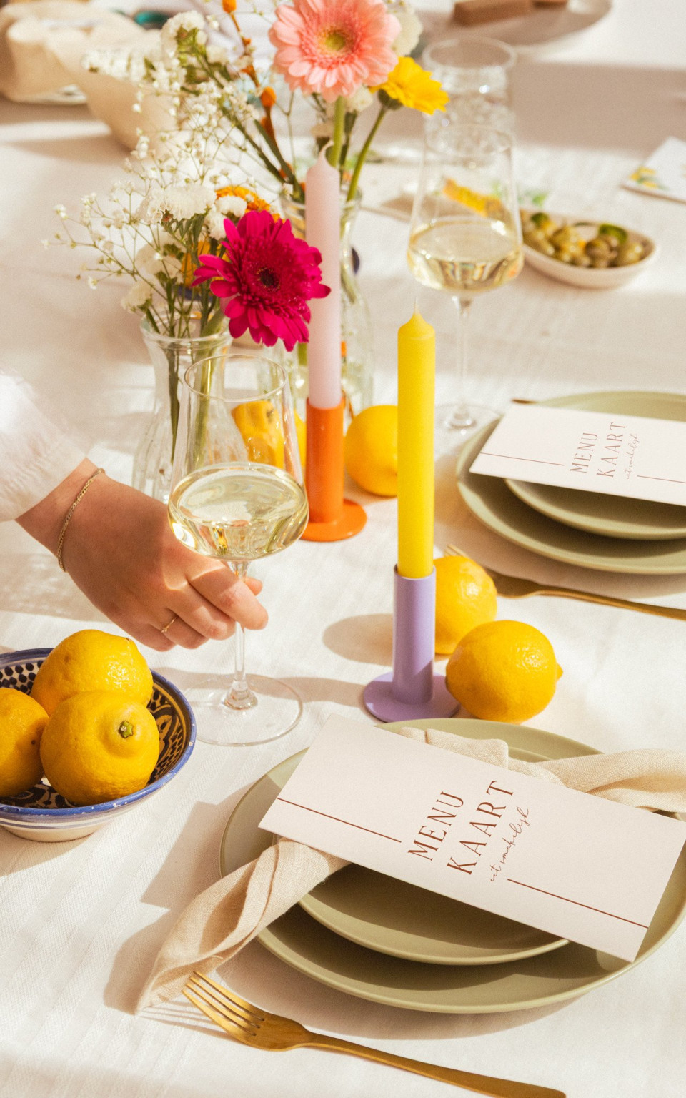 een persoon die een glas wijn vasthoudt naast een bord met citroenen