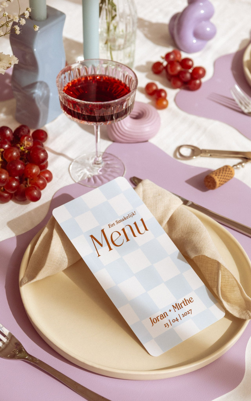 een menu dat op een bord ligt naast een glas wijn