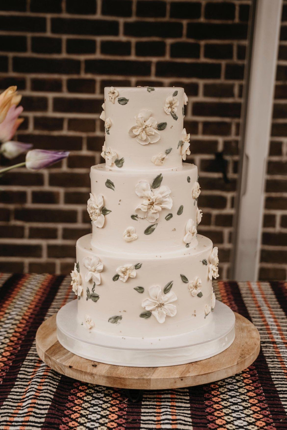 een drie-laags taart met witte bloemen erop
