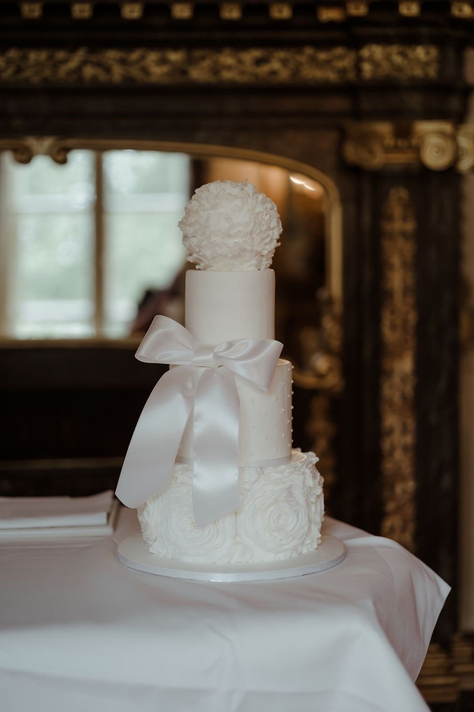 een bruidstaart met witte bloemen en een strik