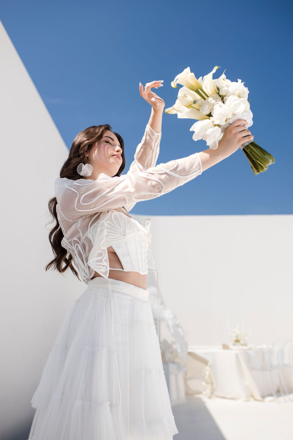 een vrouw in een witte jurk die een boeket bloemen vasthoudt