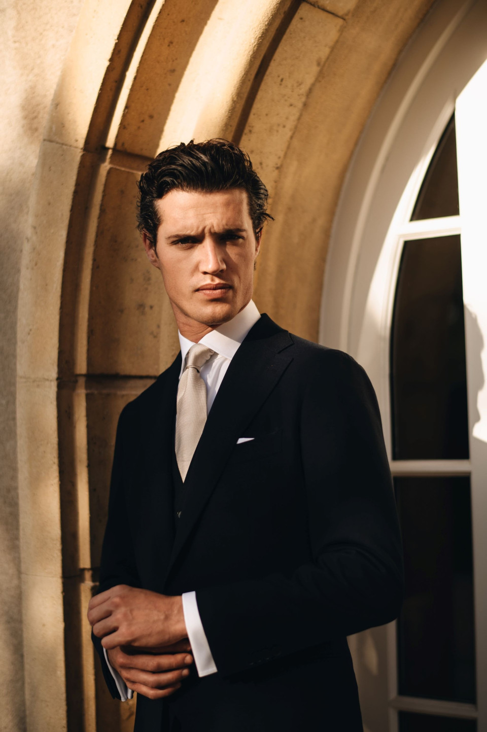 een man in een pak en stropdas die voor een raam staat