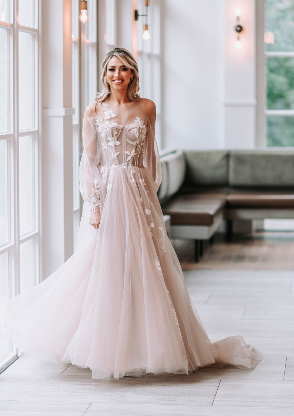 een bruid in een blozende trouwjurk poseert voor een foto