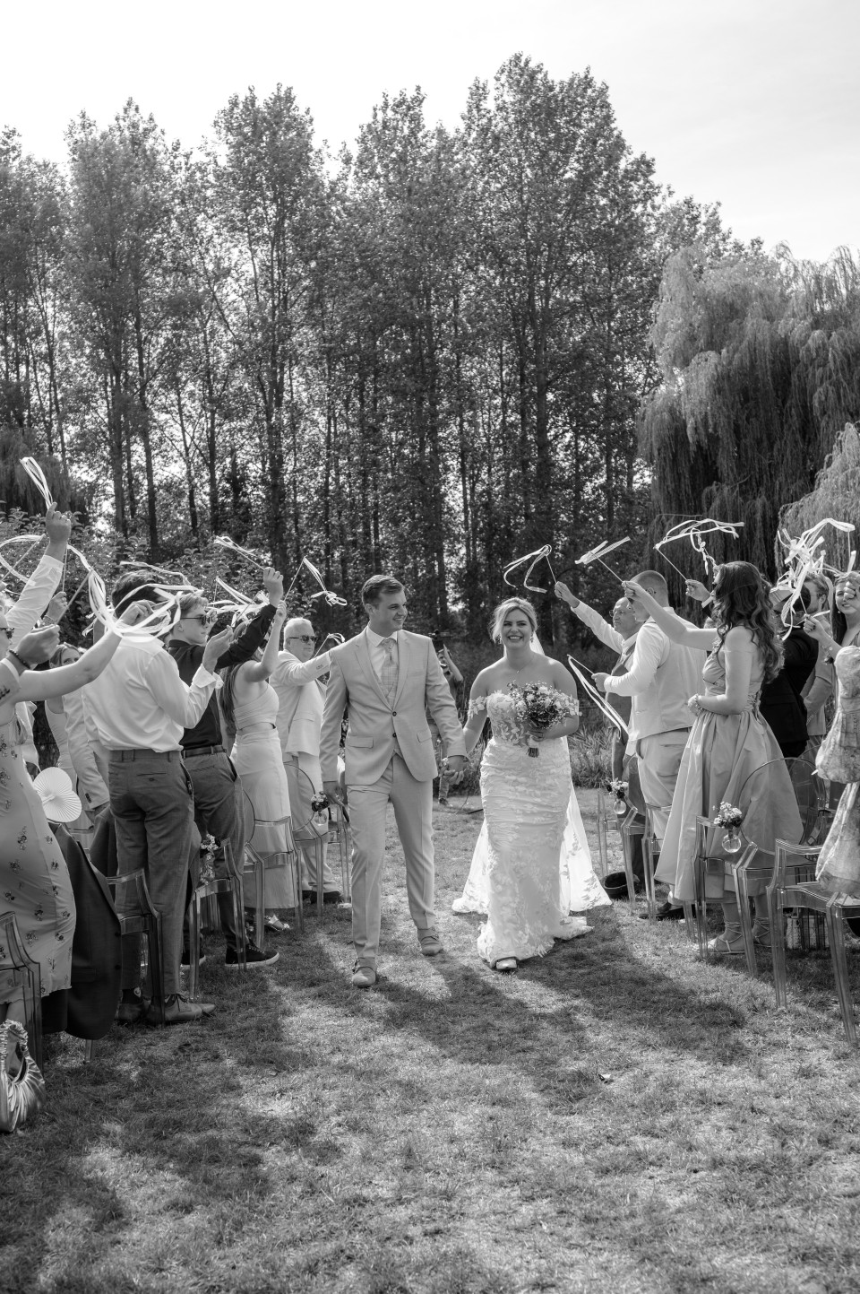 een zwart-wit foto van een bruid en bruidegom die de gang lopen